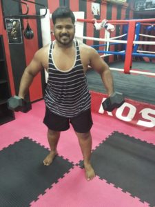 Coach Karthick posing with dumbbells in a Hulk-like pose.