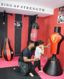 Coach Karthick guiding a young boxer on how to throw punches.