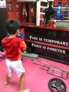 Child boxer practicing in front of a mirror