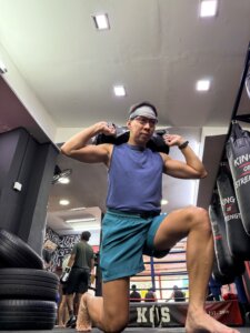guy performing weighted sandbag lunge in kos boxing gym