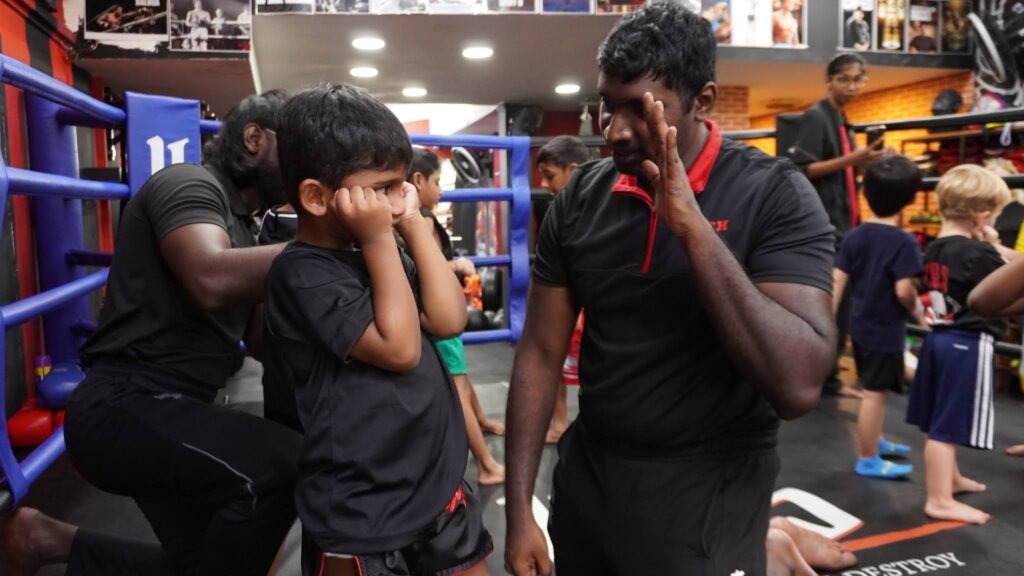 kos coach teaching junior on how to box