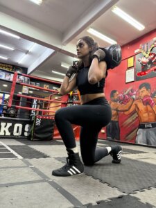 woman performing weighted sandbag lunge in boxing gym
